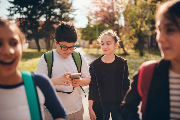 istock Boy going to school with classmates and using smart phone at schoolyard 1146217358