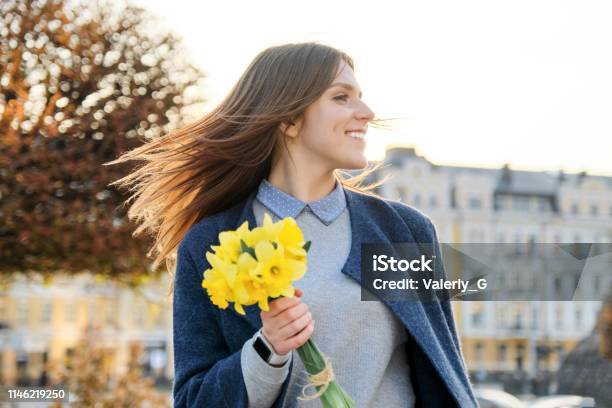 Outdoor Portrait Of Young Beautiful Girl With Bouquet Of Yellow Spring Flowers Background City Street Architecture Stock Photo - Download Image Now