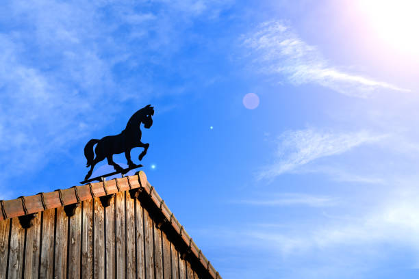 A low angle shot of a weathervane against a blue sky with clouds.