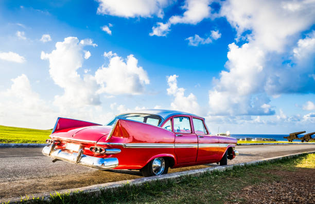白い屋根を持つアメリカの赤いビンテージカーは、カリブ海の前にハバナキューバのエル・モロ城に駐車しました-セリエキューバルポルタージュ - car stationary blue sky ストックフォトと画像