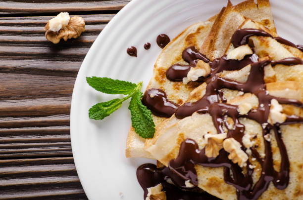 istock French crepes with chocolate sauce and walnuts in ceramic dish on wooden kitchen table 1146230522