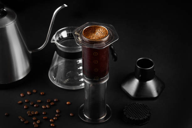 aeropress sobre fondo negro. el aeropress es un dispositivo para preparar café. la elaboración de café - coffee black coffee cup coffee bean fotografías e imágenes de stock