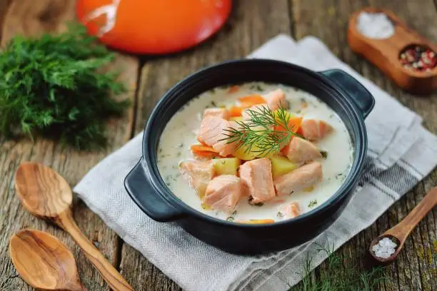 Finnish wild salmon soup with cream on an old wooden background. Rustic style.
