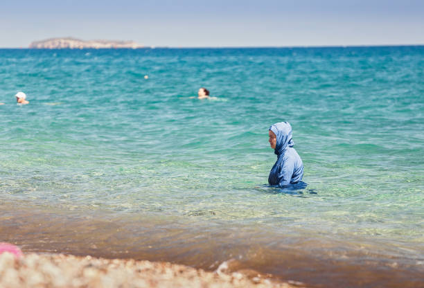 在海上的穆斯林婦女穿著一種名為布奇尼的特殊游泳衣, 現代和傳統的伊斯蘭時尚概念 - 回教泳裝 圖片 個照片及圖片檔