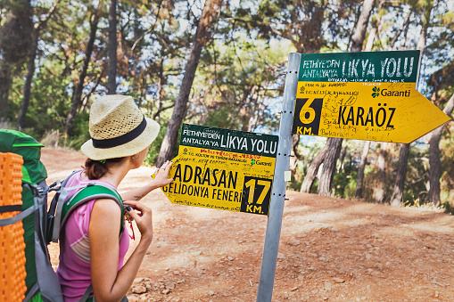 13 September 2017, Turkey, Lycian way: Woman hiker with backpack looking at the Lycian Way route sign pointing at Adrasan and Gelidonya lighthouse