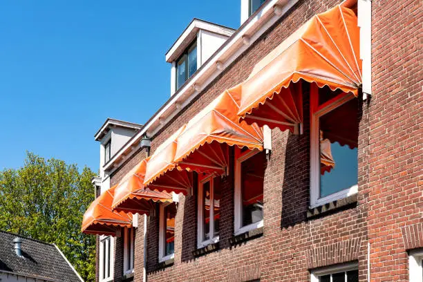 Orange awnings over the windows on a brig facade