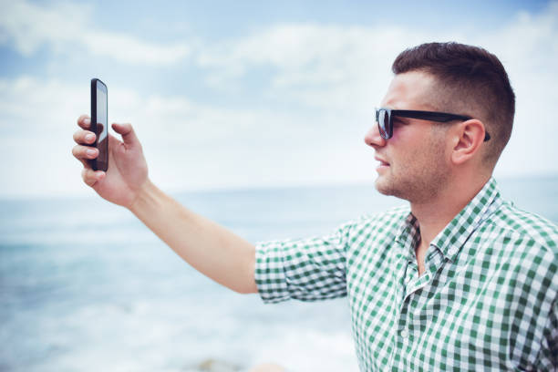 istock Man relaxing on beach in Budva Montenegro and making selfie. 1146242851