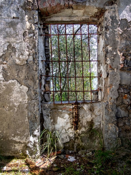 istock Old barred window with chains, beautiful nature outside. Old prison cell maybe, now ruin. 1146245139