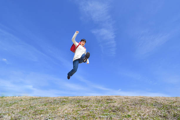 istock Japanese elementary school girl jumping in the blue sky 1146245572
