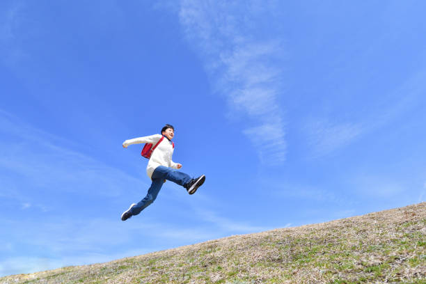istock Japanese elementary school girl jumping in the blue sky 1146245652