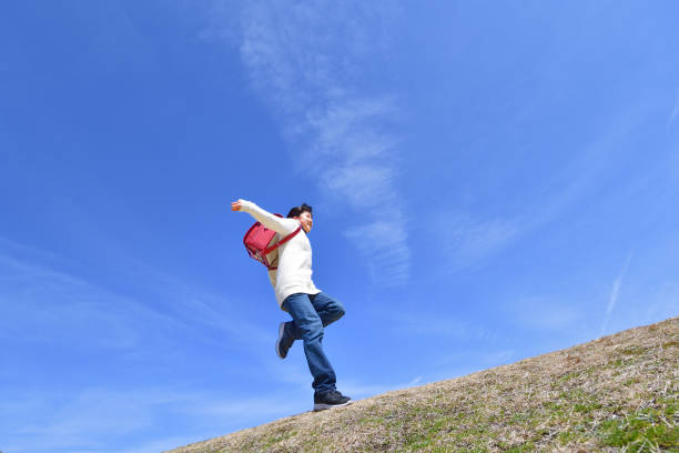 istock Japanese elementary school girl jumping in the blue sky 1146245653