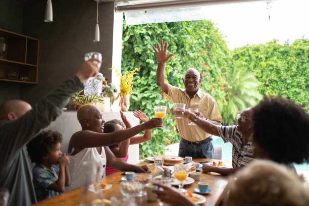 Three generations toasting in breakfast while senior man makes a speech Three generations toasting in breakfast while senior man makes a speech family reunion celebration stock pictures, royalty-free photos & images