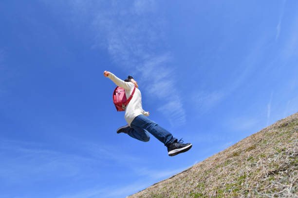 istock Japanese elementary school girl jumping in the blue sky 1146246298