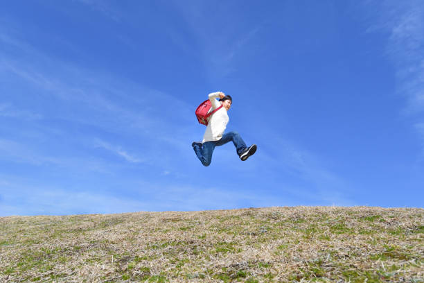 istock Japanese elementary school girl jumping in the blue sky 1146246342