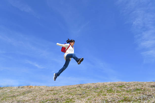istock Japanese elementary school girl jumping in the blue sky 1146246343