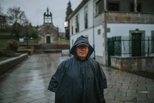 Photo of Happy senior man portrait walking with a raincoat in Galicia, Spain.