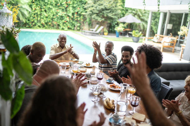 famiglia multigenerazionale che applaude durante la colazione - riunione di famiglia foto e immagini stock