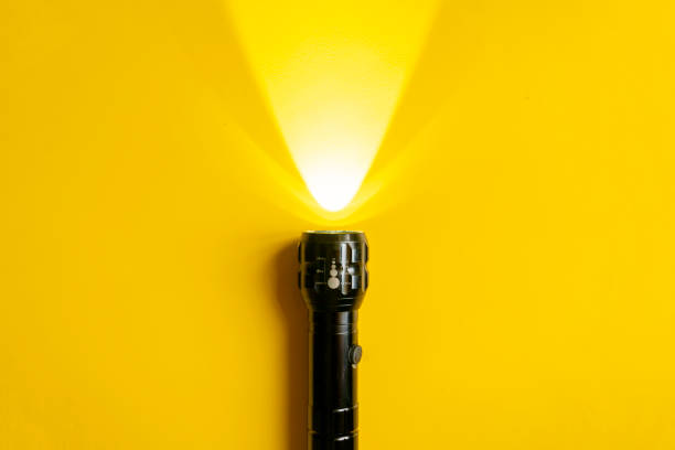 steel torch isolated on yellow surface, producing light beams or rays, copy space