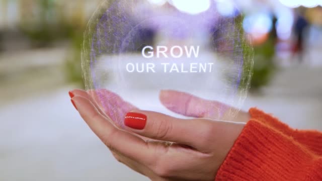 Female hands holding hologram with text Grow our talent