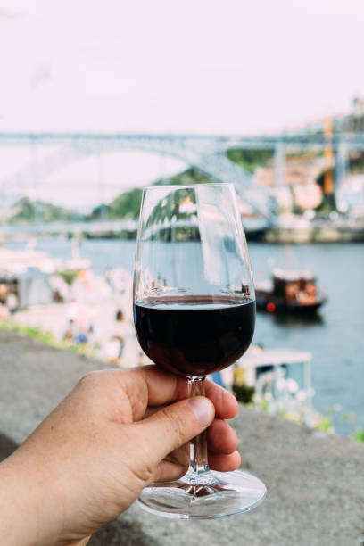 рука, держащая бокал красного вина в порту, португалия - porto built structure commercial dock port wine стоковые фото и изображения