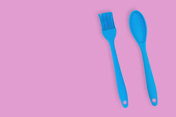 istock Blue rubber or silicone brush and spoon with plastic handles for confectionery on pink table in kitchen. Flat lay. Copy space for your text 1146255334