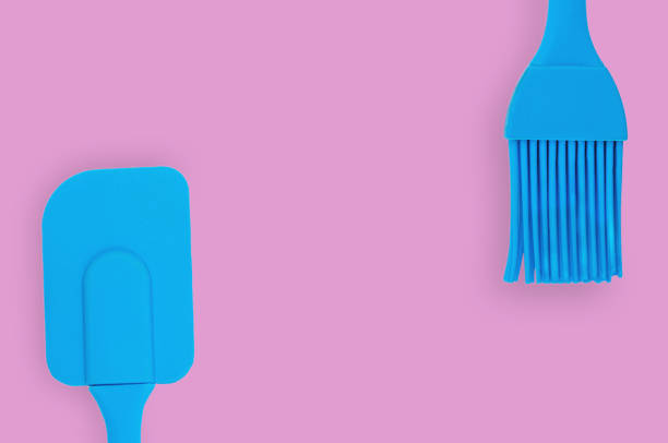 istock Blue rubber or silicone brush and spatula with plastic handles for confectionery on pink table in kitchen. Flat lay. Copy space for your text 1146255343