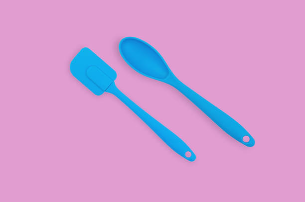 istock Blue rubber or silicone spatula and spoon with plastic handles for confectionery on pink table in kitchen. Flat lay 1146255346