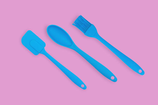 istock Blue rubber or silicone brush, spoon and spatula with plastic handles for confectionery on pink table in kitchen. Flat lay 1146255349