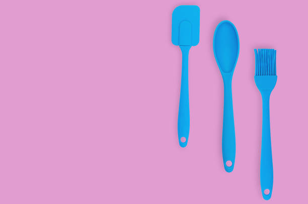 istock Blue rubber or silicone brush, spoon and spatula with plastic handles for confectionery on pink table in kitchen. Flat lay. Copy space for your text 1146255352