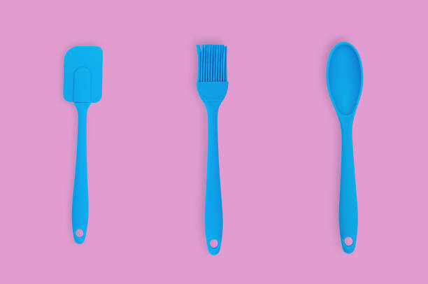 istock Blue rubber or silicone brush, spoon and spatula with plastic handles for confectionery on pink table in kitchen. Flat lay 1146255356