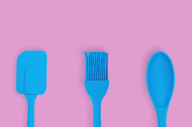 istock Blue rubber or silicone brush, spoon and spatula with plastic handles for confectionery on pink table in kitchen. Flat lay. Copy space for your text 1146255358