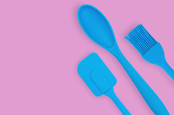 istock Blue rubber or silicone brush, spoon and spatula with plastic handles for confectionery on pink table in kitchen. Flat lay. Copy space for your text 1146255362
