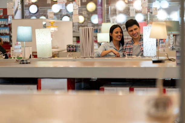 happy couple buying a lamp at a home improvement store - light shop imagens e fotografias de stock