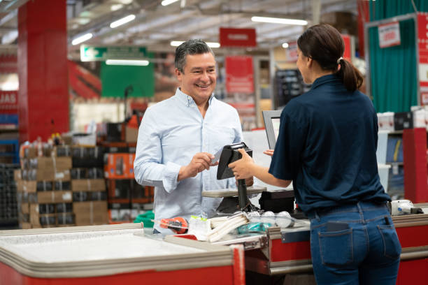 мужчина платит картой в кассе магазина по благоустройству дома - hardware store стоковые фото и изображения