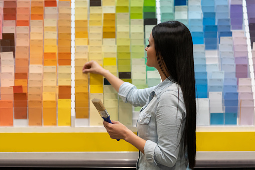 Portrait of a woman at home improvement store choosing a color to paint her house and looking at some samples