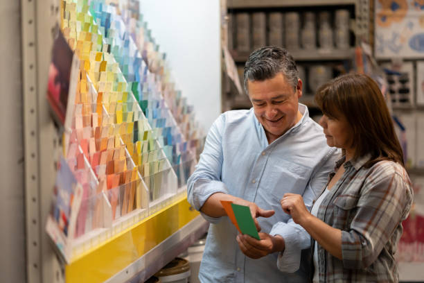 Loving couple at home improvement store choosing a color to paint their house Portrait of a loving couple at home improvement choosing a color to paint their house and holding a palette - decoration concepts hardware store stock pictures, royalty-free photos & images