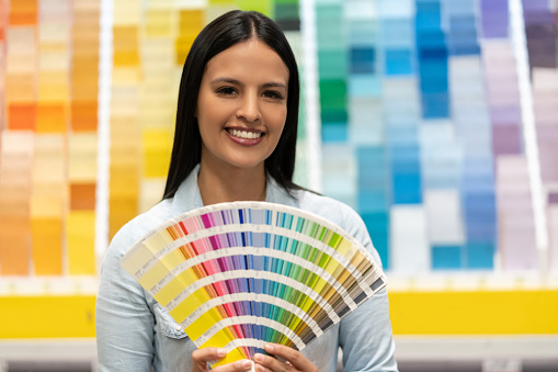 Portrait of a woman at home improvement store choosing a color to paint her house and holding a palette