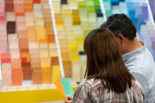 Portrait of a couple at home improvement store choosing a color to paint their house and looking at samples - decoration concepts