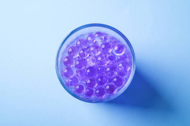 istock Purple marbles in drinking transparent glass blue background top view 1146261890