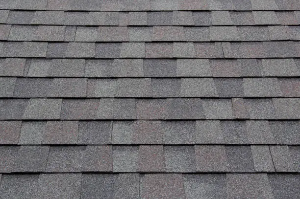 Photo of dark new roof shingle background and texture. asphalt tiles of house roof.