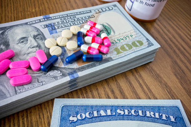 Medical expenses Medicine pills on a pile of 100 dollar bills and social security card social security social security card identity us currency stock pictures, royalty-free photos & images