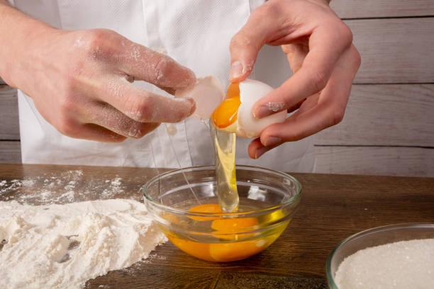 istock Cook breaks eggs into a glass bowl, closeup 1146272987