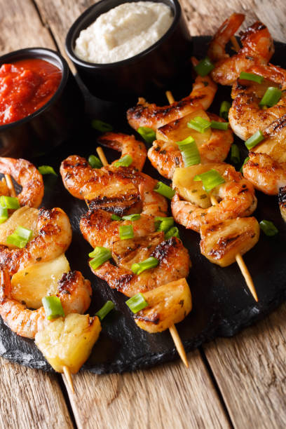 istock Delicious shrimp kebab with pineapples served with two sauces close-up on a table. vertical 1146273072