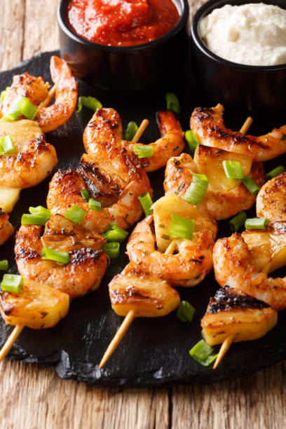 istock Spicy shrimp kebab with pineapples served with two sauces close-up. vertical 1146273743