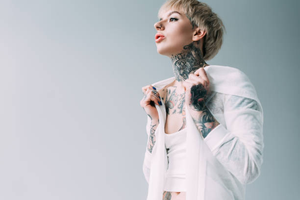istock blonde woman with tattoos standing isolated on grey 1146274637