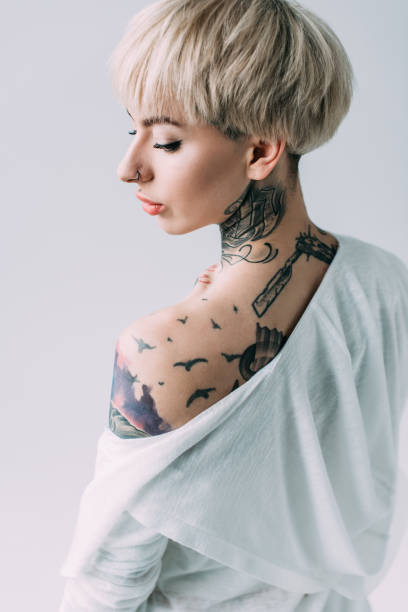 istock attractive woman with tattoos on back standing isolated on grey 1146274640