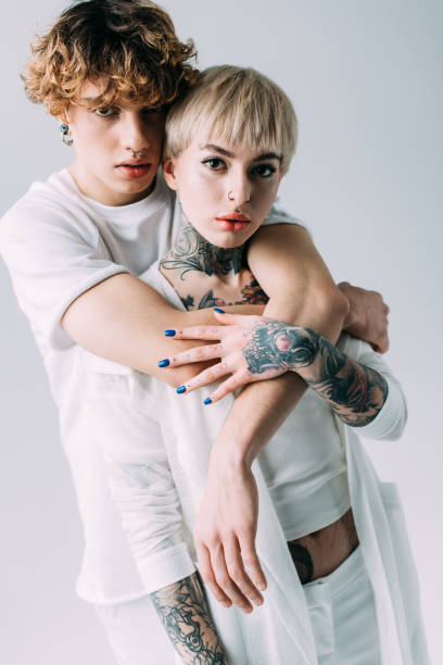 istock man with curly hair hugging girlfriend with tattoos isolated on grey 1146274705