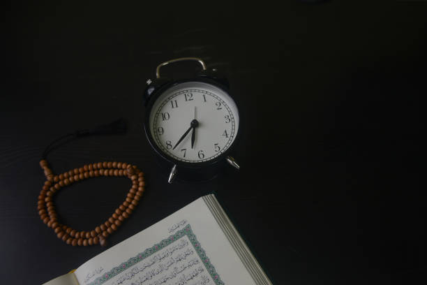 Al-Quran, Beads and clock with black table top wood background