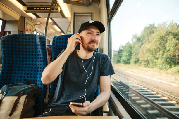 A young man listens to a music or podcast while traveling in a train.