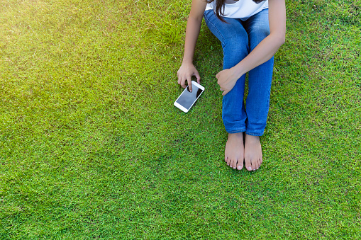Woman using mobile smart phone on the grass for relaxing with social media